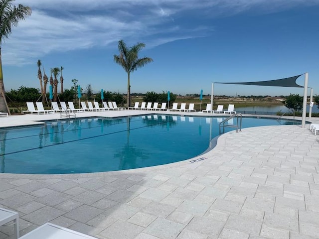 view of swimming pool featuring a water view and a patio