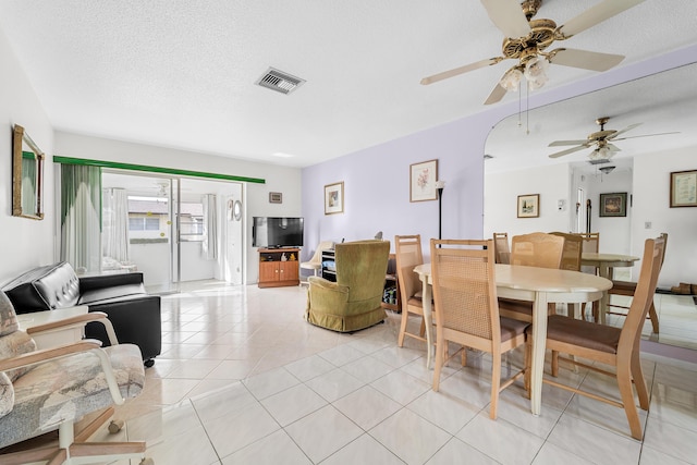 dining area featuring ceiling fan, light tile patterned flooring, and a textured ceiling