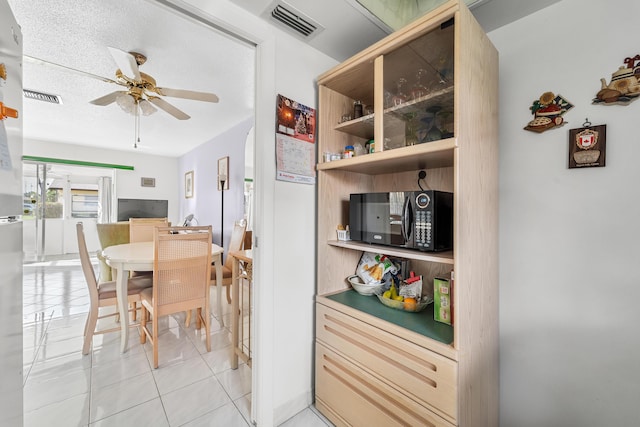 kitchen featuring a textured ceiling, ceiling fan, and light tile patterned flooring