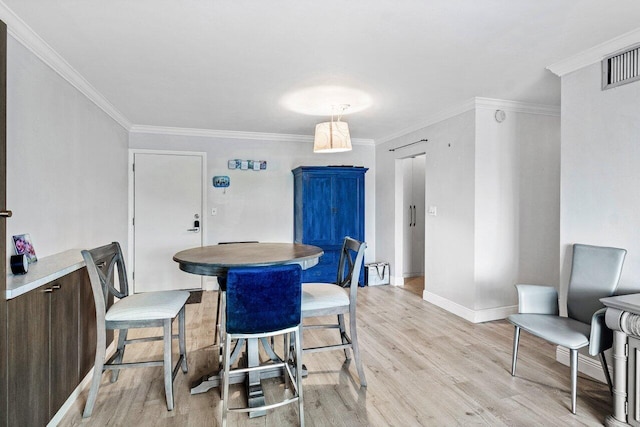 dining space with light wood-type flooring and crown molding