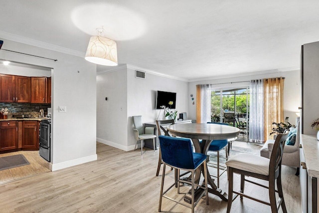 dining space featuring light hardwood / wood-style floors and crown molding