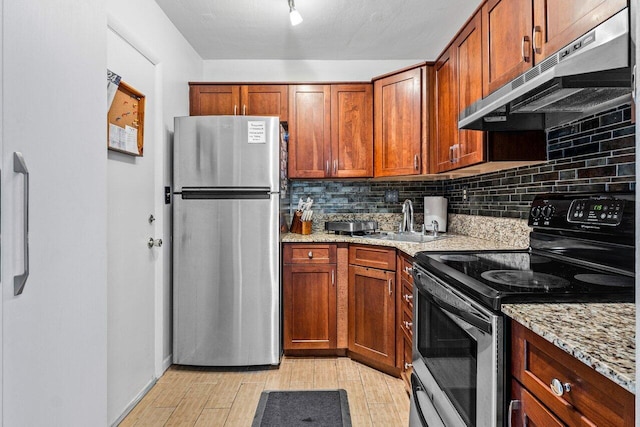 kitchen with appliances with stainless steel finishes, tasteful backsplash, light stone counters, sink, and light hardwood / wood-style flooring