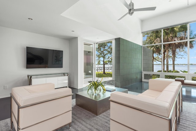 living room with a water view, ceiling fan, and a healthy amount of sunlight