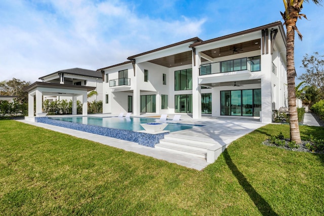 rear view of property featuring ceiling fan, a patio, a balcony, and a lawn