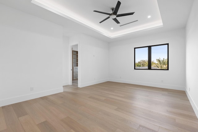 unfurnished room with ceiling fan, a raised ceiling, and light hardwood / wood-style flooring