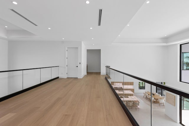 hallway featuring a tray ceiling and light hardwood / wood-style flooring