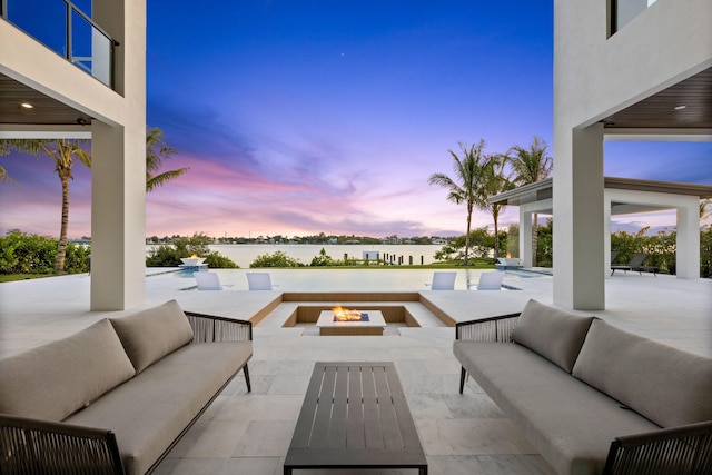 patio terrace at dusk with an outdoor living space with a fire pit and a water view