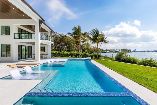 view of swimming pool featuring a patio, a water view, and a lawn