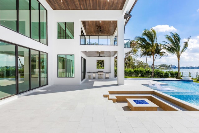 back of house featuring a water view, area for grilling, an outdoor fire pit, ceiling fan, and a patio