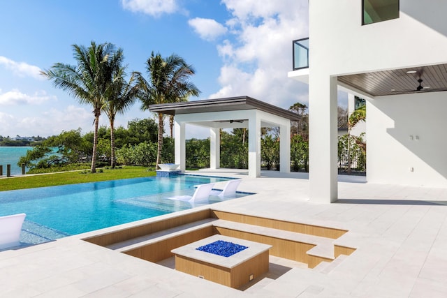 view of swimming pool with a patio, ceiling fan, and a fire pit