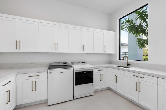 laundry area with cabinets, washing machine and clothes dryer, and sink