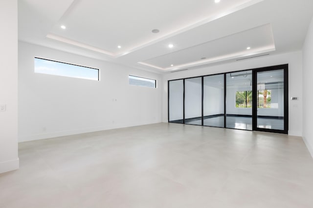 unfurnished room featuring a tray ceiling and a wealth of natural light