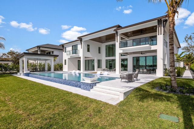 back of property with a swimming pool with hot tub, a lawn, ceiling fan, a patio area, and a balcony