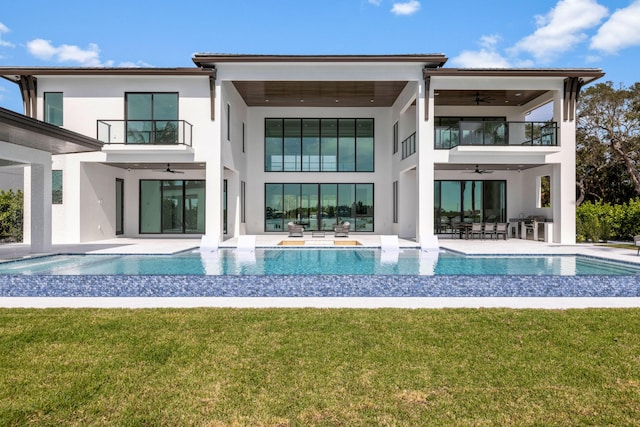 rear view of property featuring a balcony, a yard, and ceiling fan