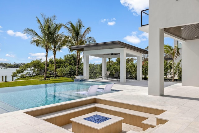 view of swimming pool featuring a gazebo, ceiling fan, an outdoor fire pit, and a patio area