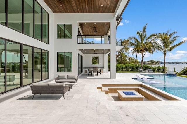 exterior space with ceiling fan, a water view, a patio area, an outdoor living space with a fire pit, and a balcony