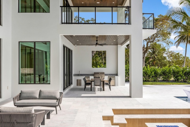 view of patio / terrace featuring grilling area, a balcony, ceiling fan, an outdoor living space, and exterior kitchen