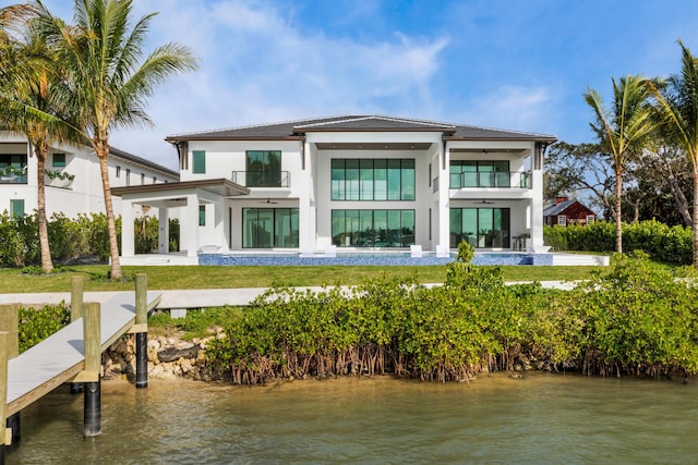 back of property with a water view, a balcony, and a yard