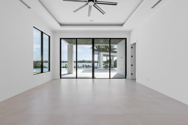 unfurnished room with a raised ceiling, a wealth of natural light, and ceiling fan