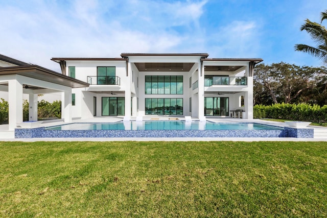 back of property with a balcony, a patio, and a lawn