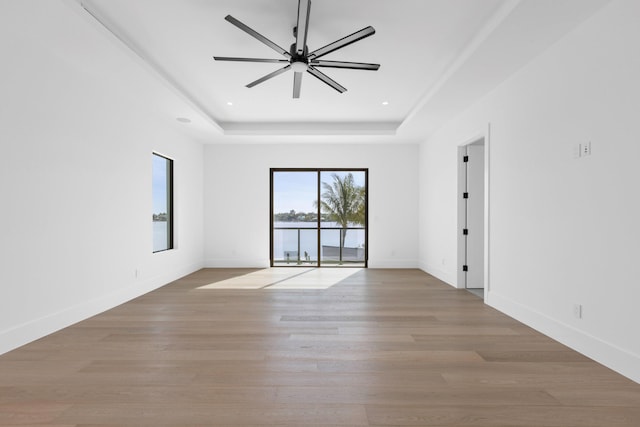 unfurnished room featuring light hardwood / wood-style flooring, a raised ceiling, and ceiling fan