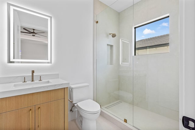 bathroom with ceiling fan, tiled shower, vanity, and toilet