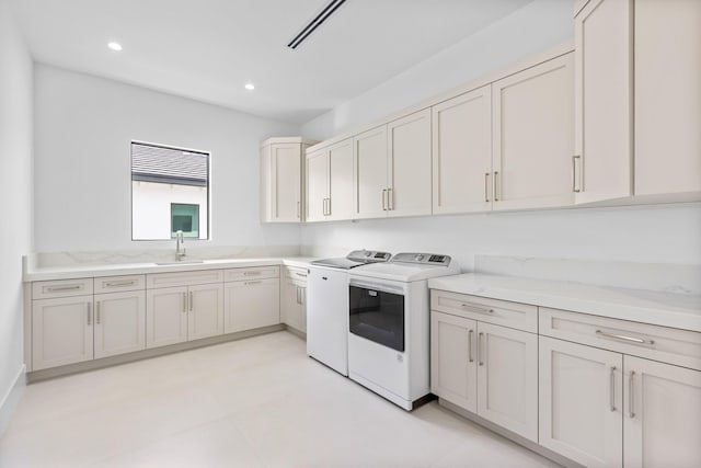 clothes washing area with cabinets, sink, and independent washer and dryer