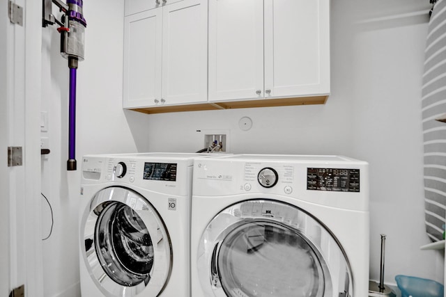 washroom with washer and dryer and cabinets