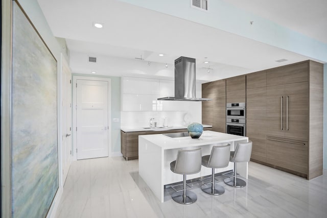 kitchen with a kitchen island, a kitchen bar, decorative backsplash, white cabinets, and island range hood