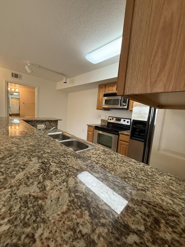 kitchen with sink, track lighting, stainless steel appliances, and a textured ceiling