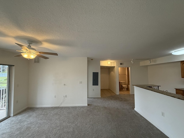 unfurnished living room featuring carpet flooring, electric panel, ceiling fan, and a textured ceiling