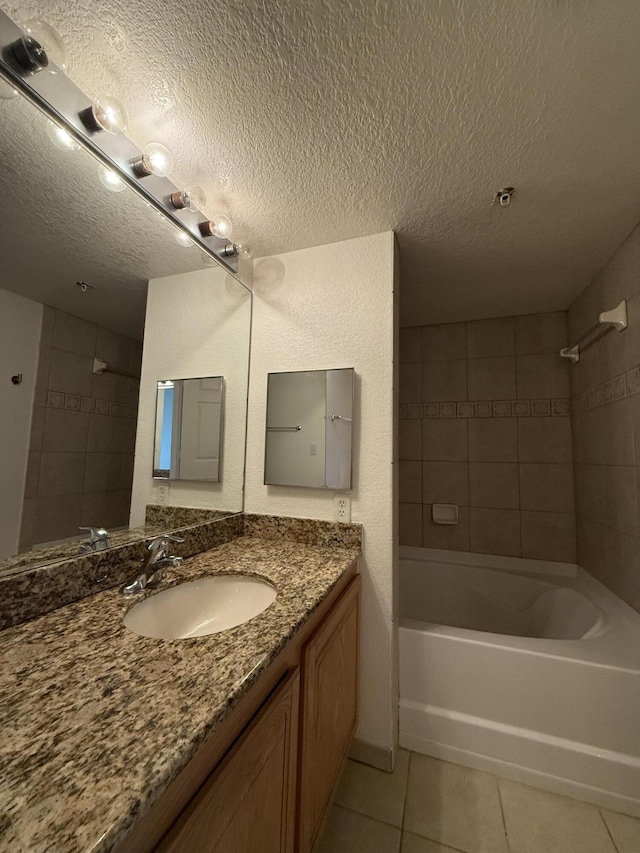 bathroom with tile patterned flooring, tiled shower / bath combo, a textured ceiling, and vanity