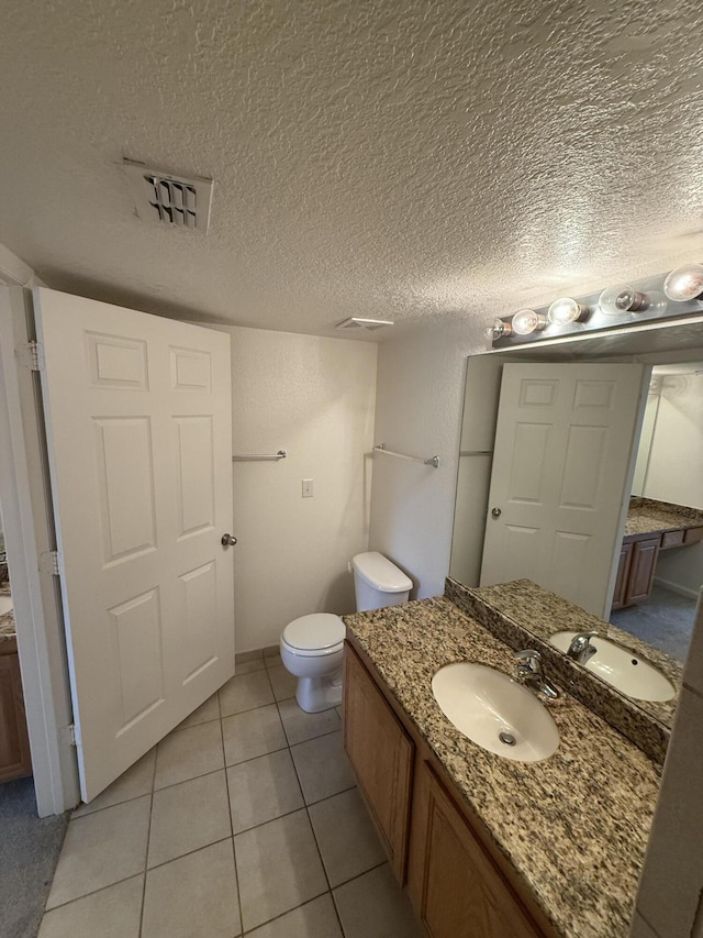 bathroom with toilet, a textured ceiling, vanity, and tile patterned floors