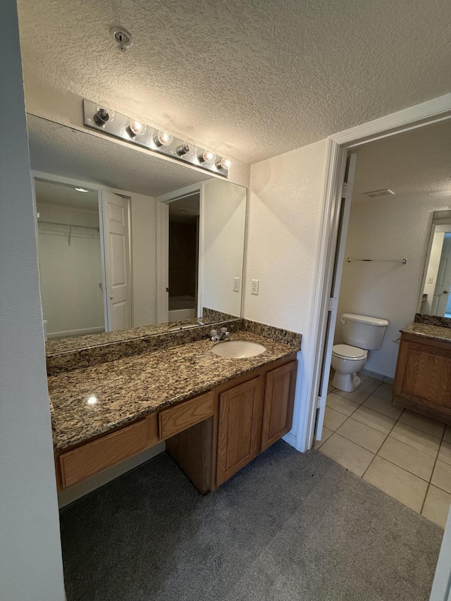 bathroom featuring tile patterned flooring, vanity, toilet, and a textured ceiling