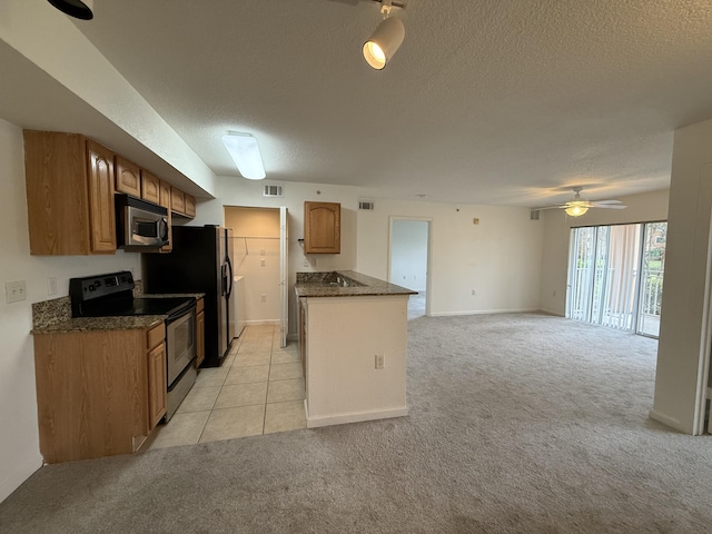 kitchen with light carpet, a textured ceiling, stainless steel appliances, and ceiling fan