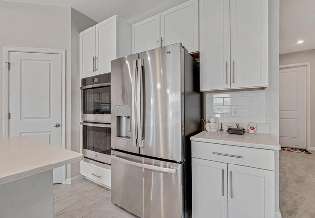 kitchen with decorative backsplash, appliances with stainless steel finishes, and white cabinetry