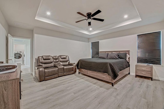 bedroom featuring a raised ceiling, ceiling fan, light hardwood / wood-style flooring, and washer / dryer