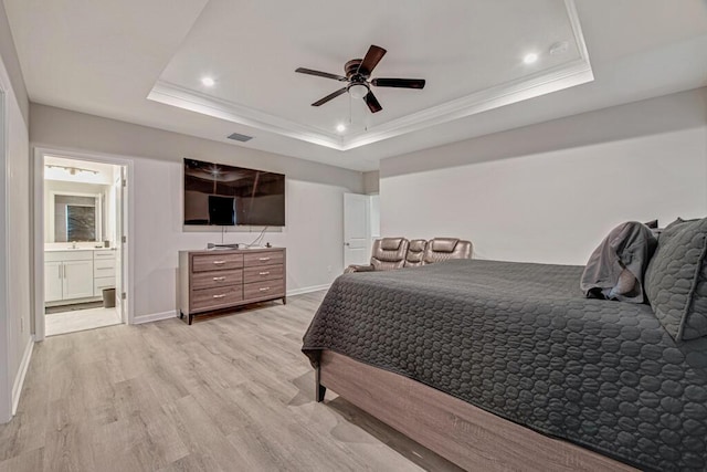 bedroom with ensuite bathroom, ornamental molding, a raised ceiling, ceiling fan, and light hardwood / wood-style flooring