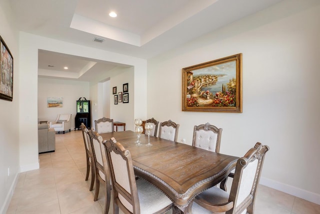 dining room with light tile patterned floors and a tray ceiling