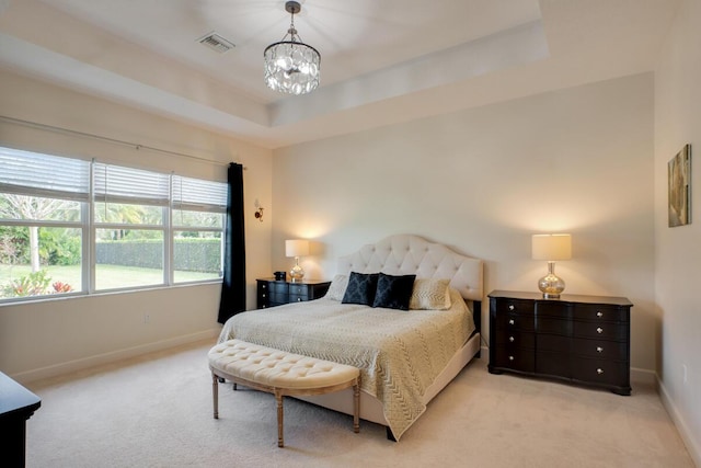 carpeted bedroom with a tray ceiling and an inviting chandelier