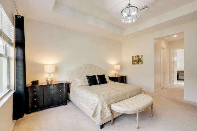 bedroom featuring a raised ceiling, multiple windows, light colored carpet, and an inviting chandelier