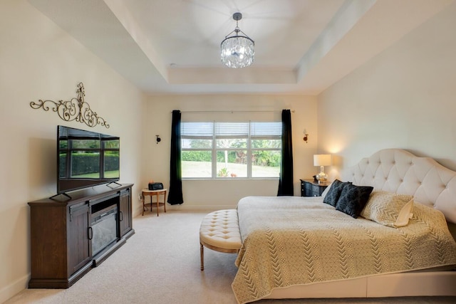 carpeted bedroom featuring an inviting chandelier and a raised ceiling