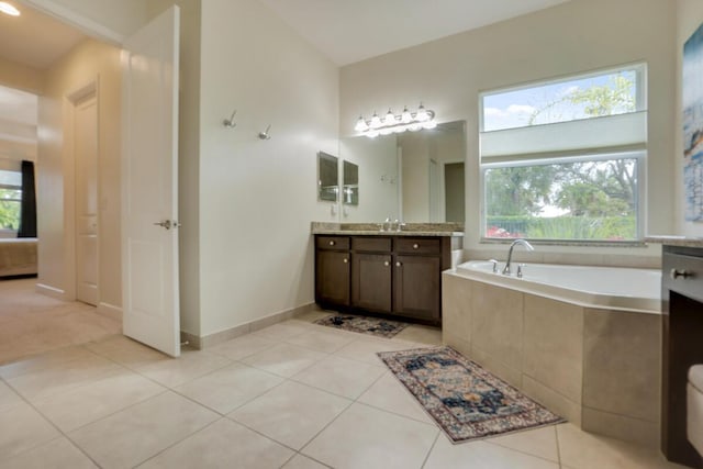 bathroom featuring tile patterned floors, vanity, and tiled bath