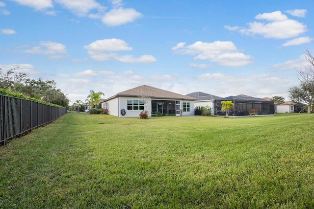 rear view of property featuring a lanai and a yard