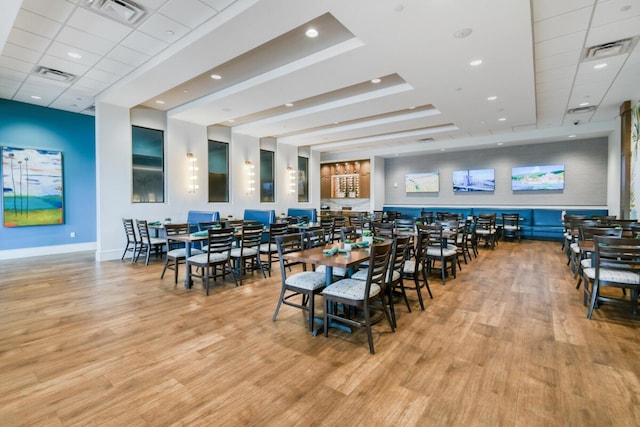 dining room with light wood-type flooring and a paneled ceiling