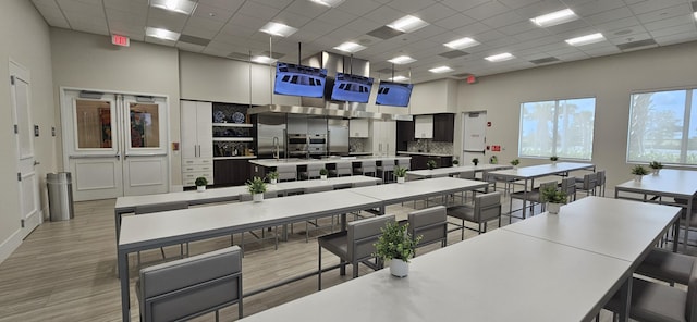 kitchen with a drop ceiling, backsplash, a spacious island, light hardwood / wood-style floors, and a kitchen bar