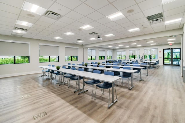 interior space featuring a paneled ceiling, a healthy amount of sunlight, and light hardwood / wood-style floors