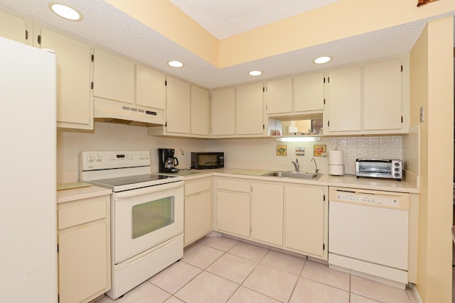 kitchen with sink, cream cabinetry, a textured ceiling, white appliances, and light tile patterned flooring