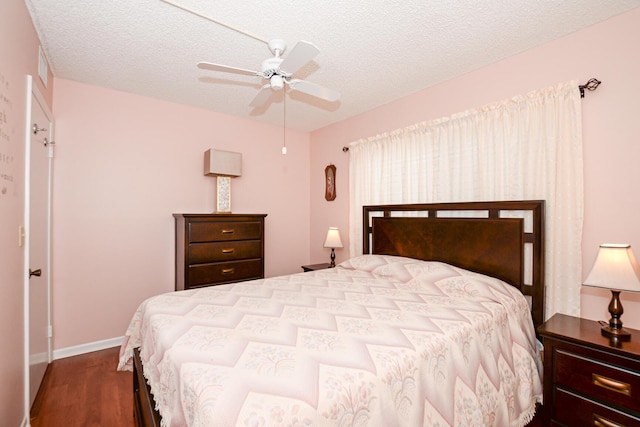 bedroom with ceiling fan, wood-type flooring, and a textured ceiling