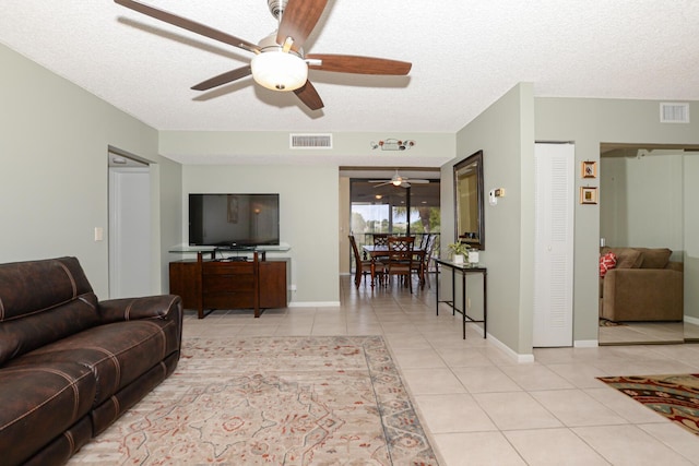 tiled living room featuring ceiling fan and a textured ceiling